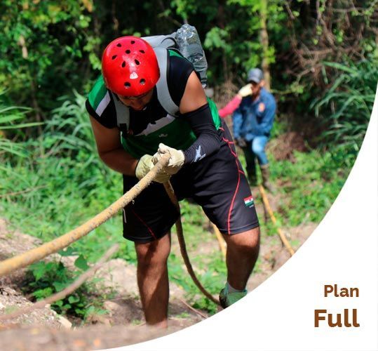 Persona con casco y equipo haciendo rapel, sujetando una cuerda. Se ve otra persona al fondo.