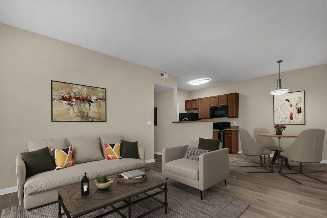 Modern open-plan living room with gray sofa, armchair, coffee table, and kitchen in the background