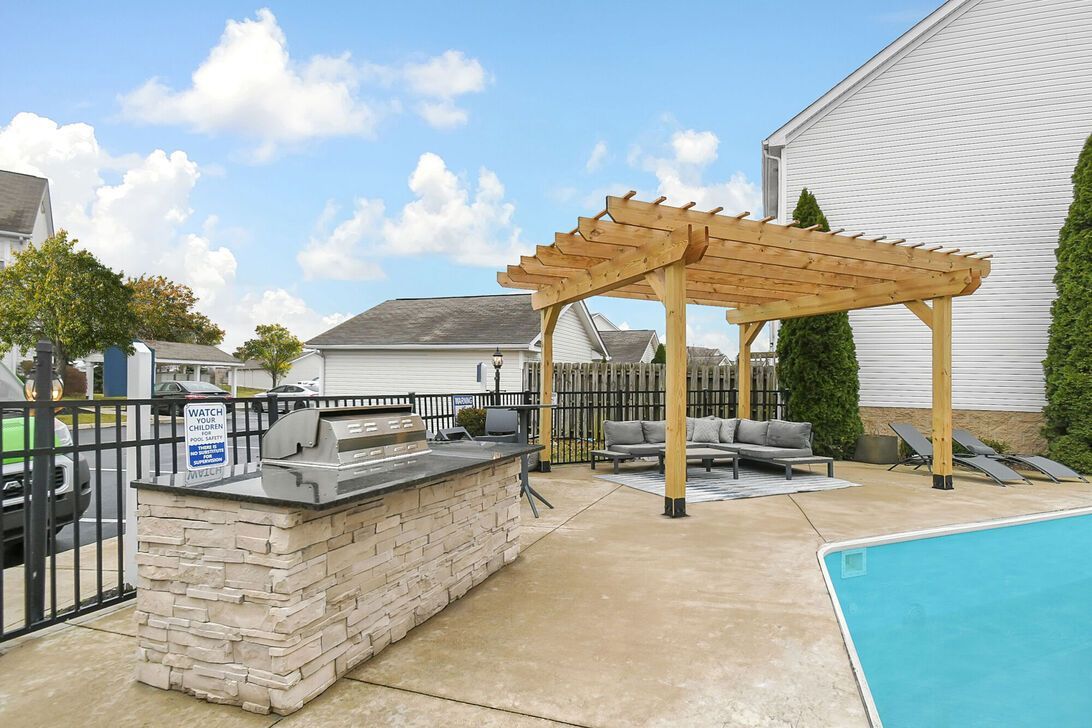 Backyard patio with pergola beside a swimming pool and hot tub under a blue sky