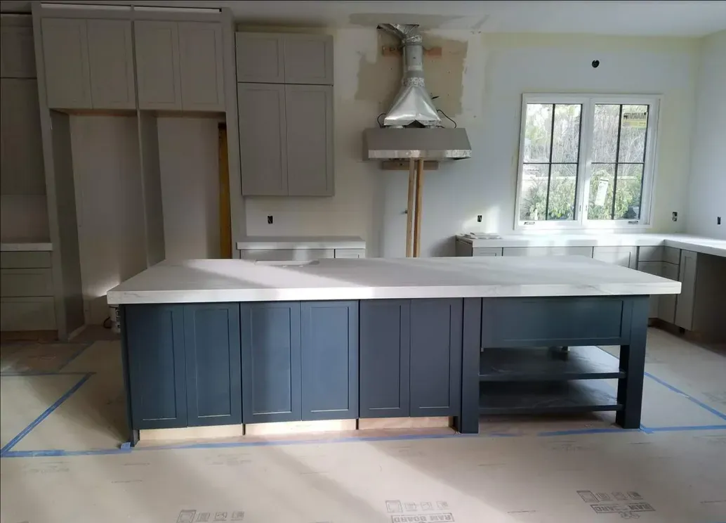 A kitchen under construction with a large island in the middle.