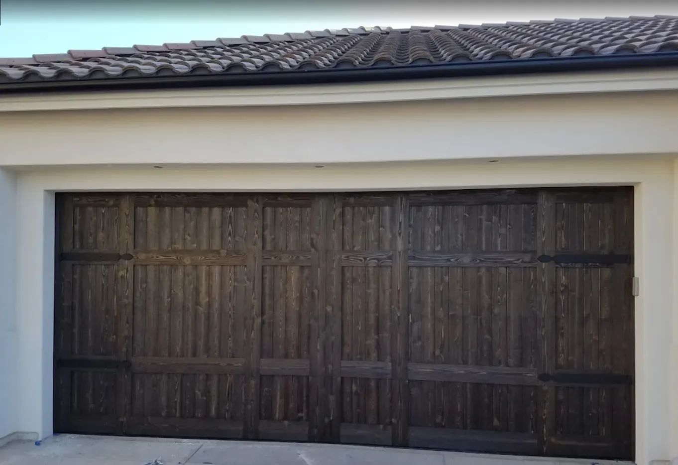 The garage door is made of wood and has a tile roof.