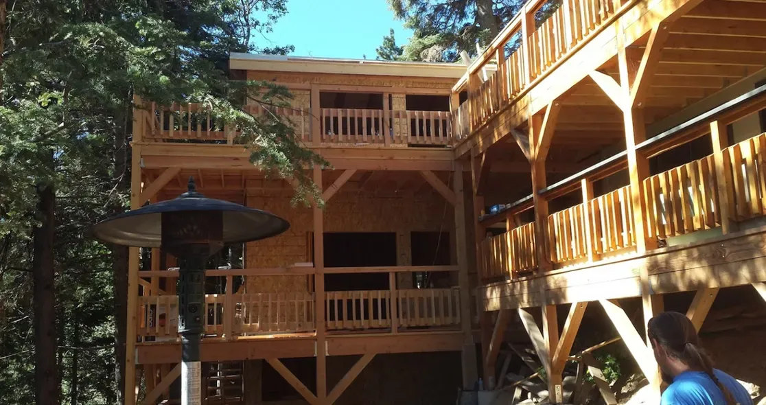 A man standing in front of a large wooden house