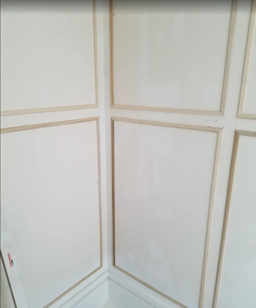 A corner of a room with white paneling and gold trim.