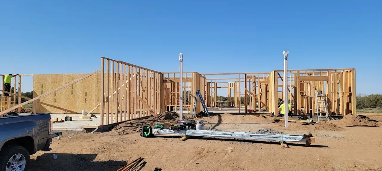 A truck is parked in front of a house under construction.