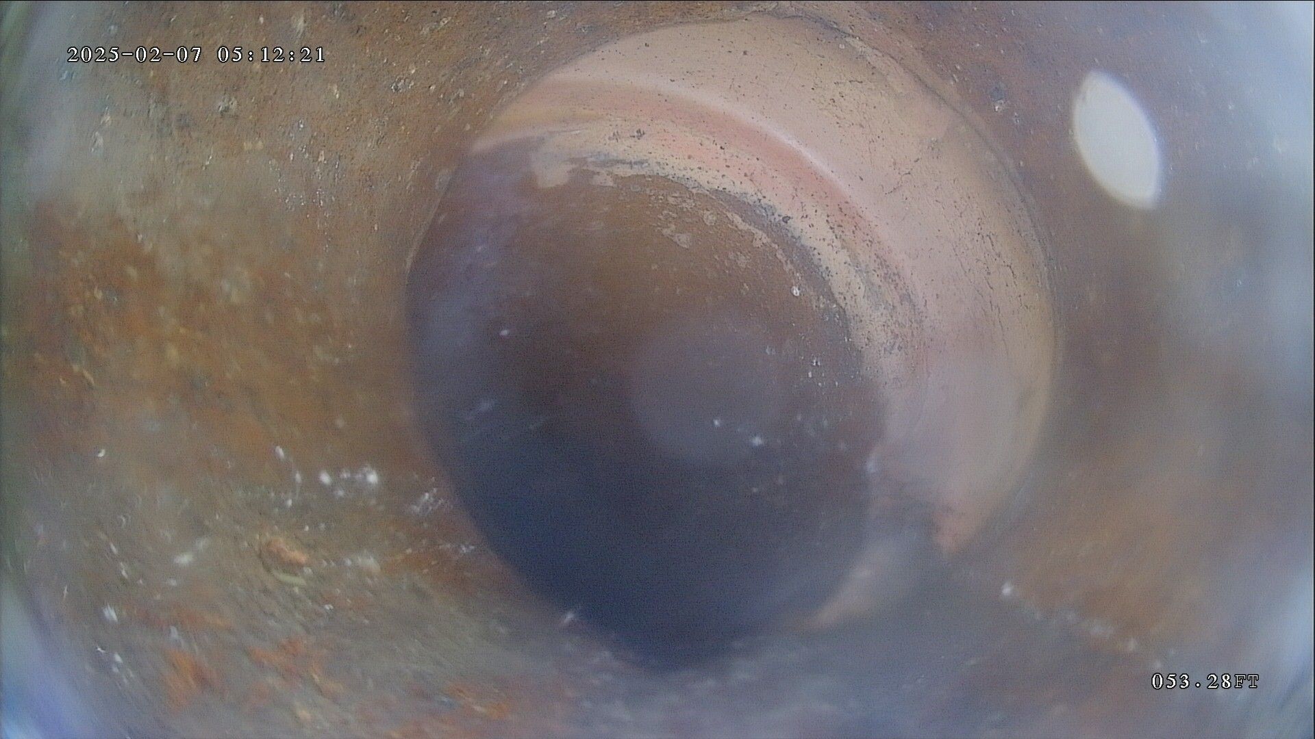 Close-up view inside a pipe. A dark, circular object is visible, possibly a blockage, surrounded by the pipe's interior.