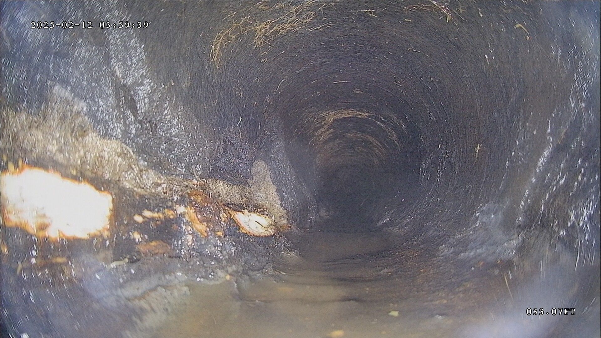 Inside view of a dark pipe with rough, stained walls.