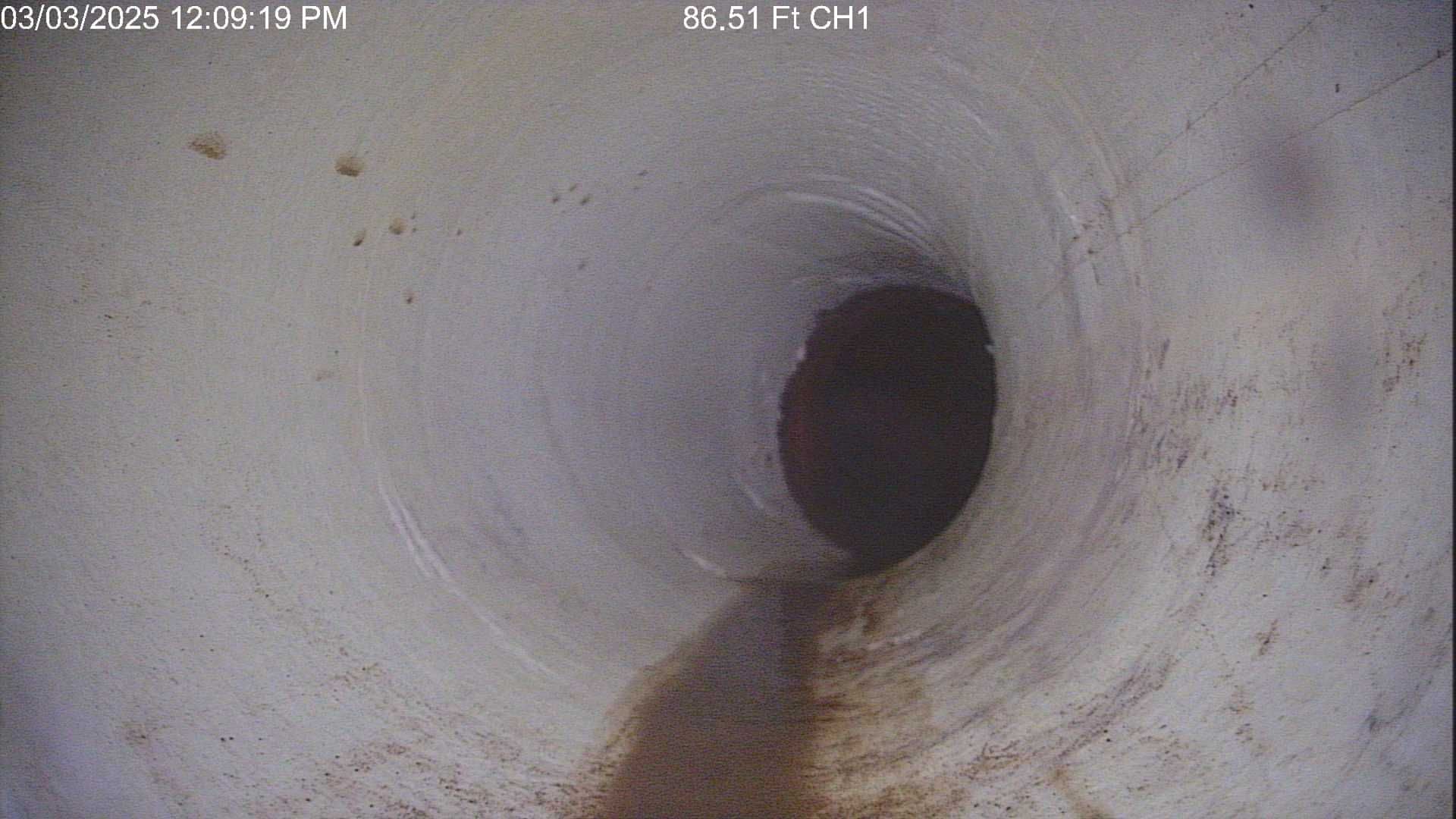 Grey PVC pipes being installed in a dirt trench outdoors.