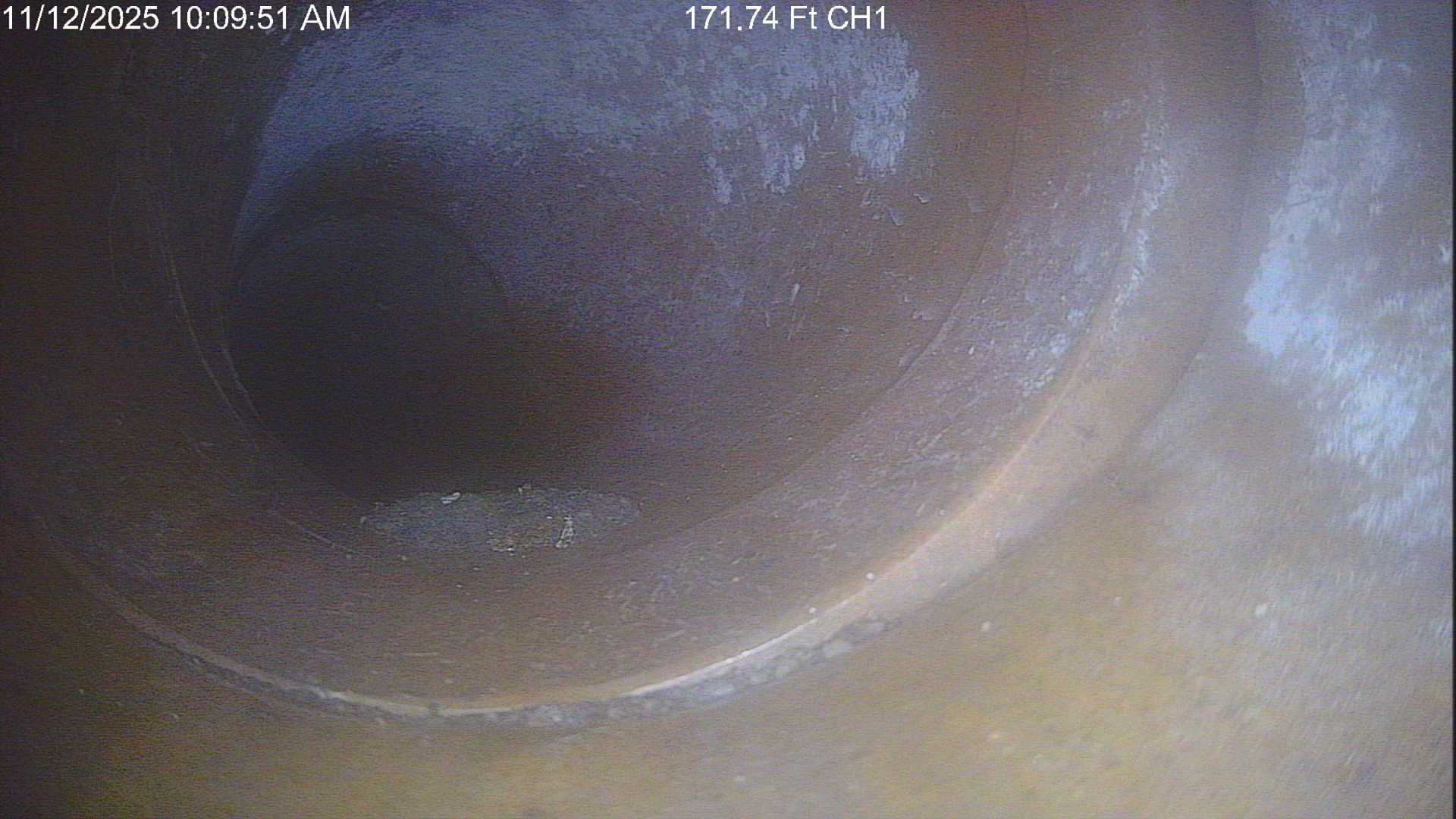 Inside of a pipe, showing a dark central opening surrounded by light-colored, possibly mineral, deposits.