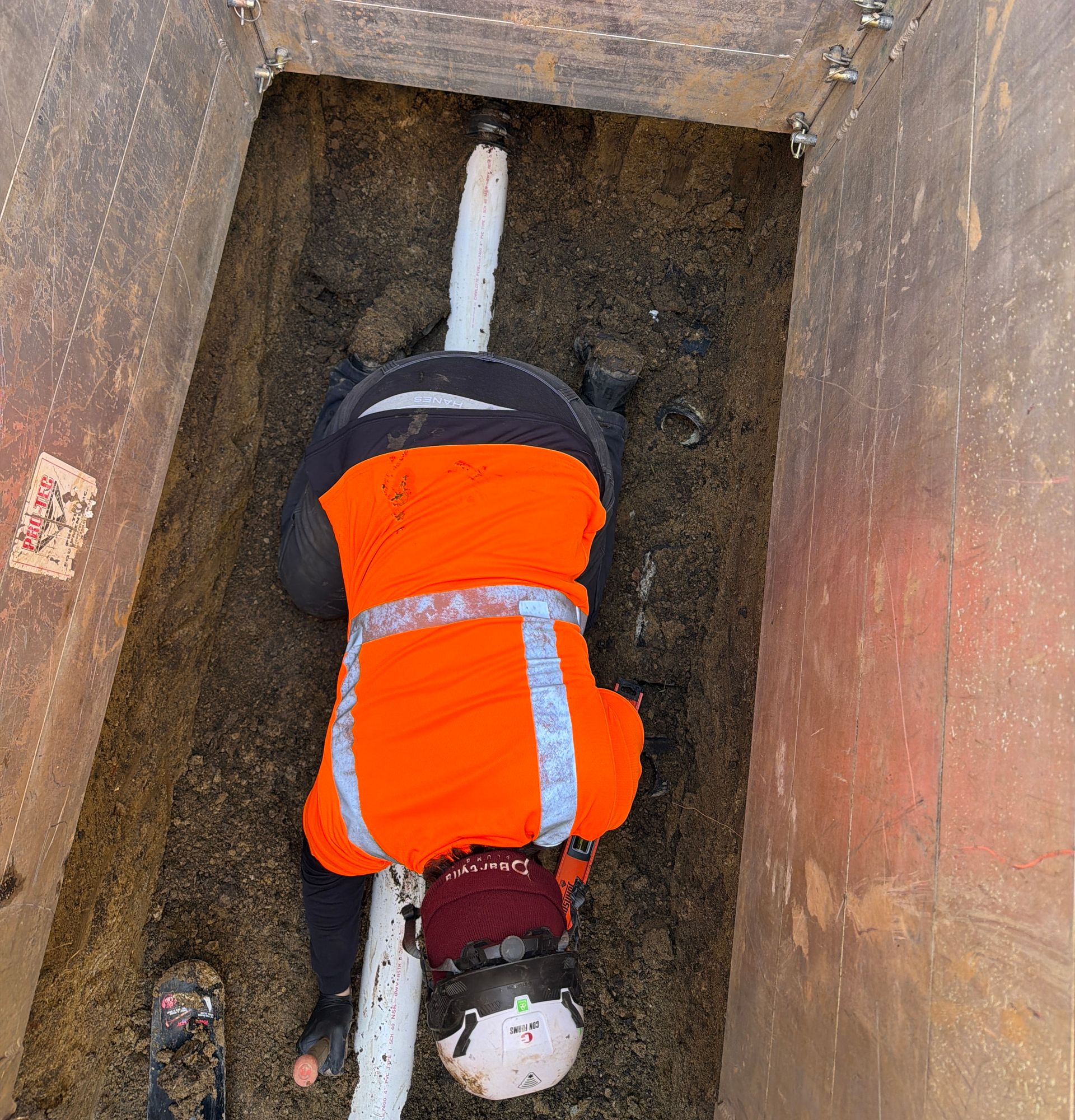 A man is kneeling down bedding off a pipe