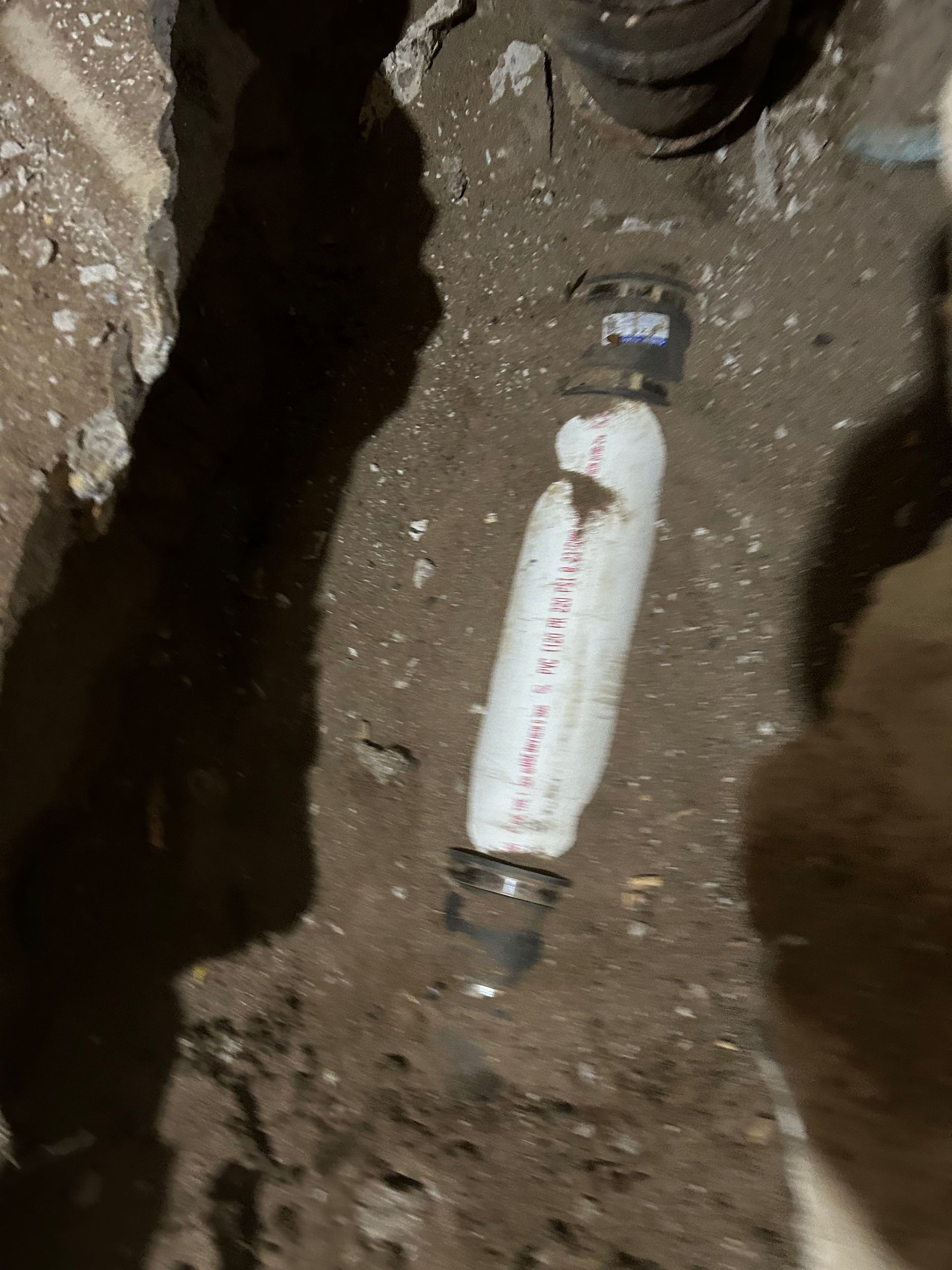 PVC pipe repair in a dirt trench, with couplings visible.