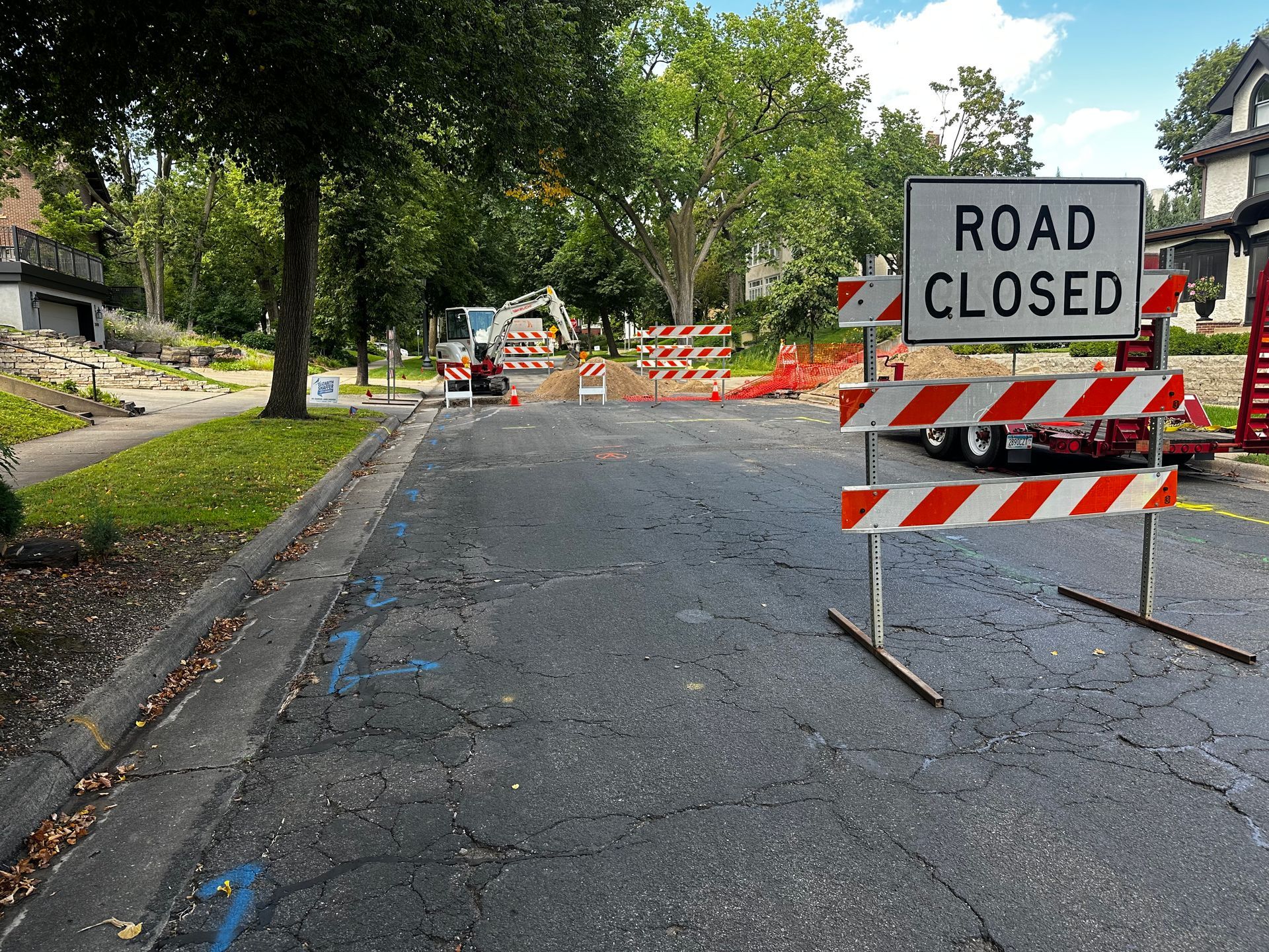 Road closed sign on a street with construction equipment in the distance.