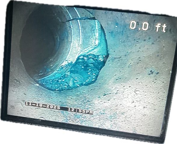 Blue-tinged, obstructed pipe interior. A large, blue-colored mass blocks a section, with the pipe opening visible.