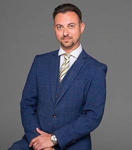 A man is holding a dog in his arms and the dog is wearing a sweater.