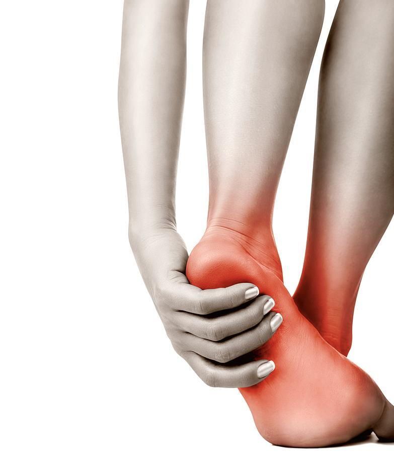 A woman is holding her foot in pain.