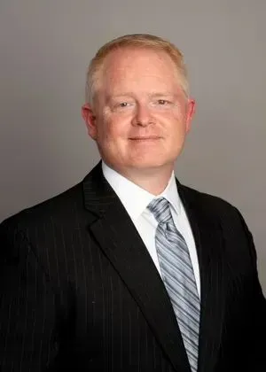A man in a suit and tie is smiling for the camera.