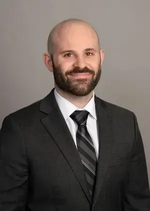 A bald man with a beard is wearing a suit and tie.