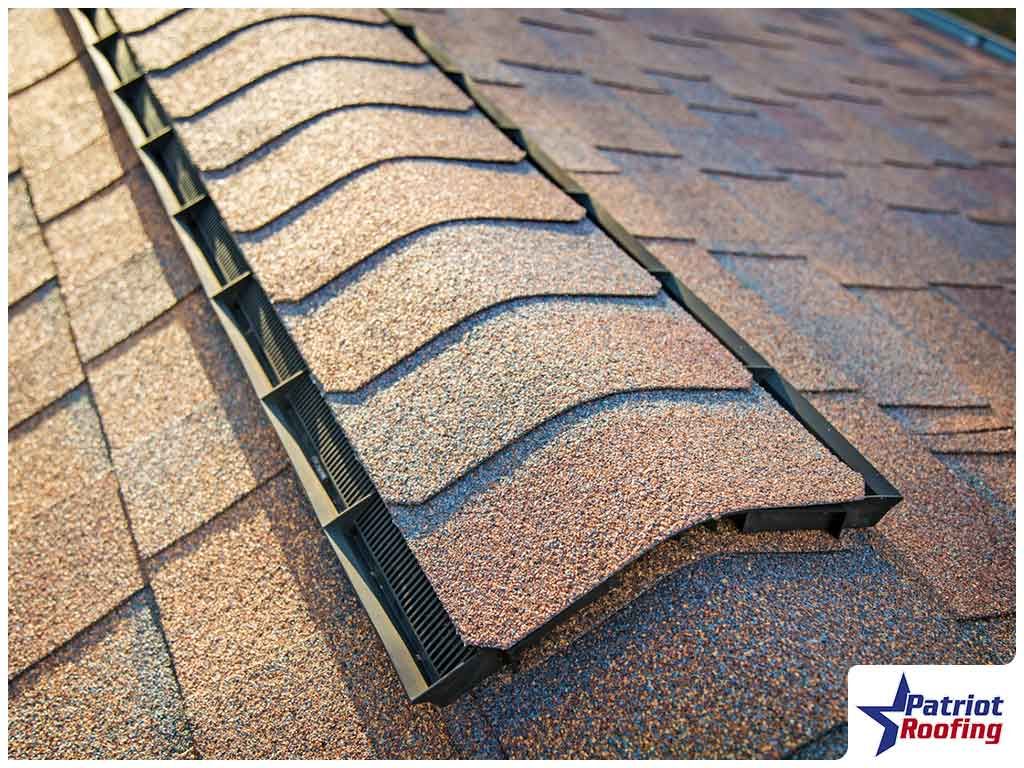 A close up of a roof with shingles and a vent on it.