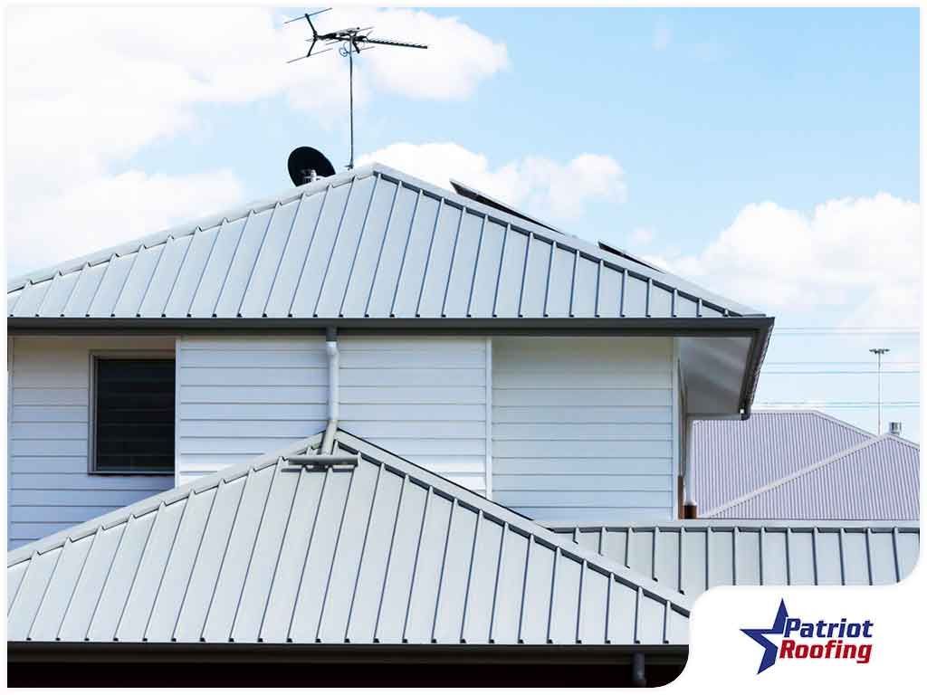 A picture of a white house with a patriot roofing logo in the corner