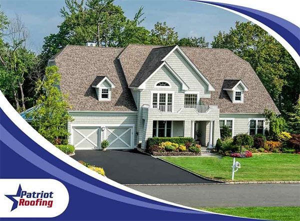 A large white house with a patriot roofing logo in the corner