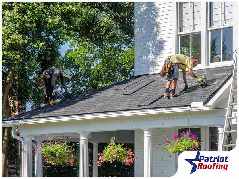 Two men are working on the roof of a house.