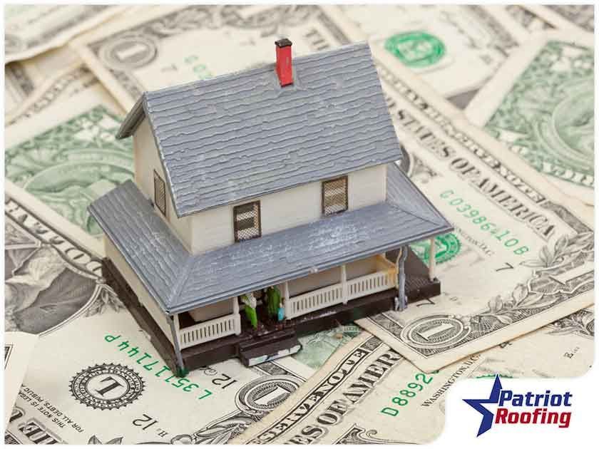 A model house is sitting on top of a pile of money