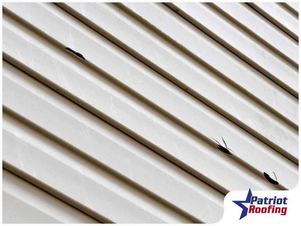 A close up of a white siding with holes in it