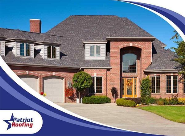 A large brick house with a patriot roofing logo in the corner