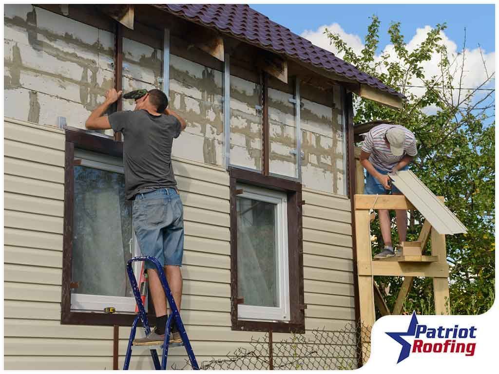 Two men are working on the side of a house.
