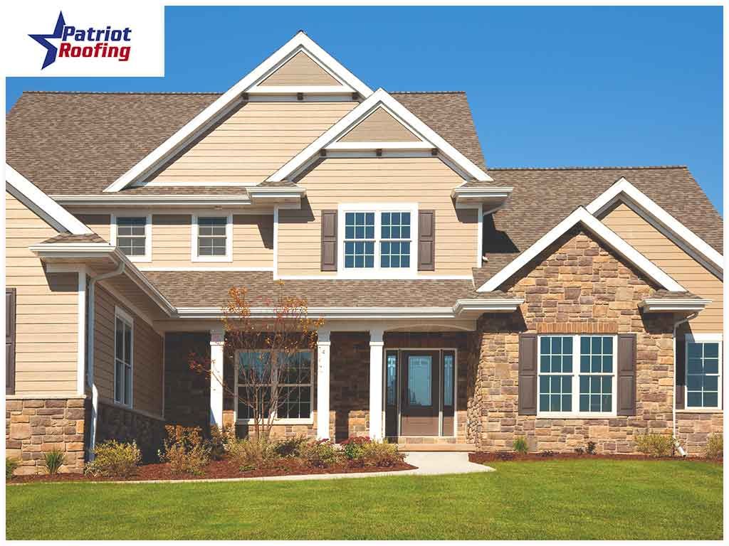 A large house with a patriot roofing logo behind it