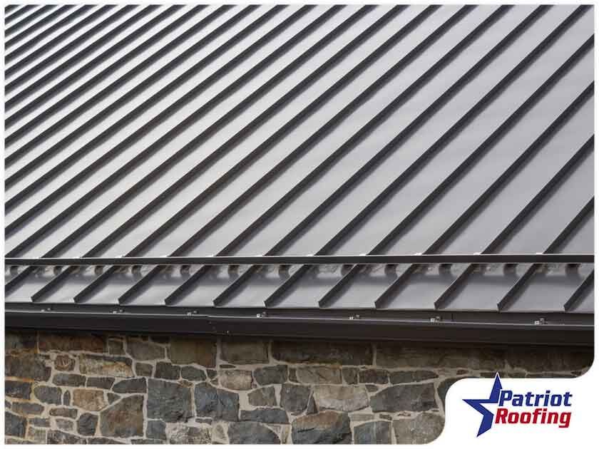 A close up of a metal roof on a building with a stone wall.