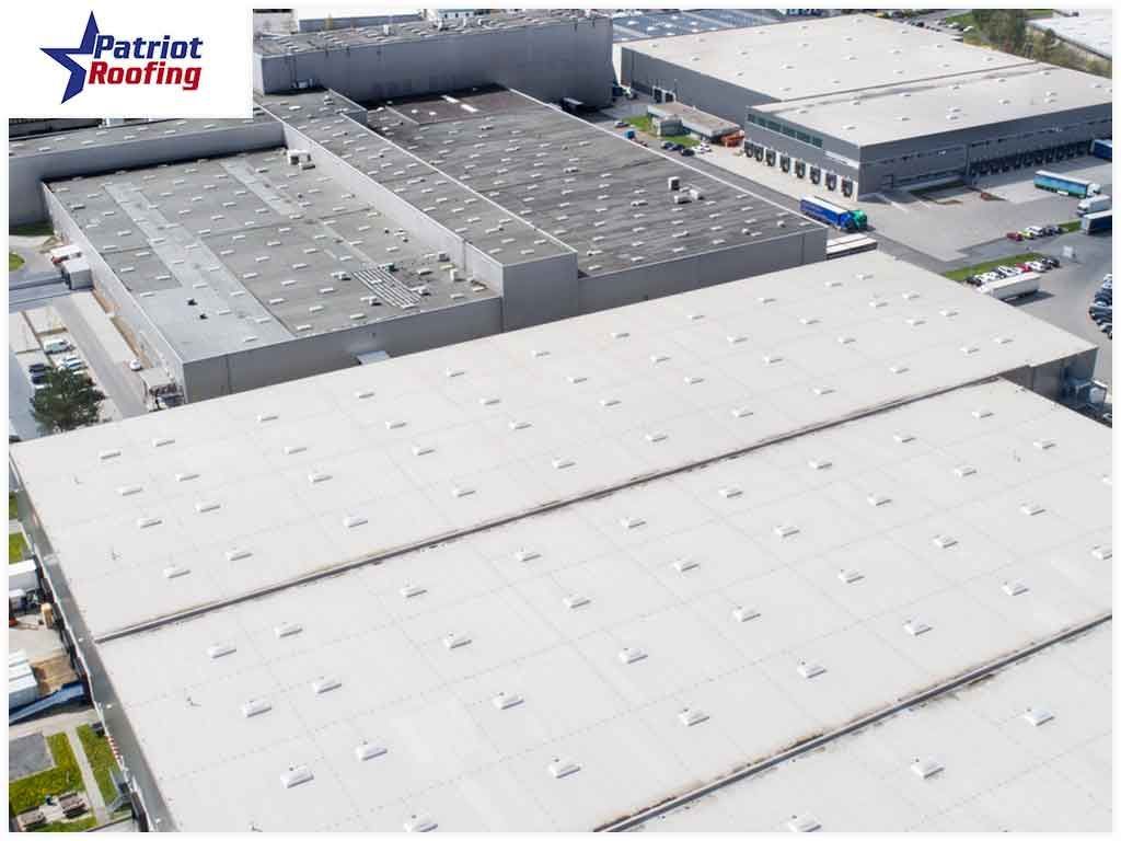 An aerial view of a large building with a patriot roofing logo in the corner