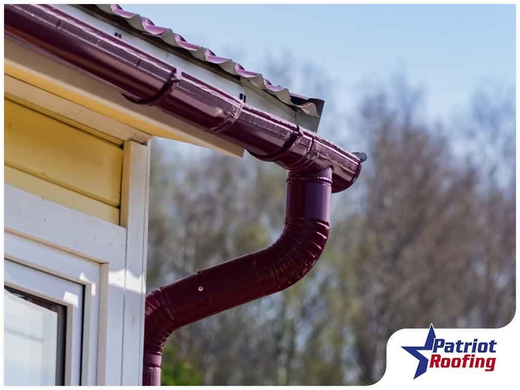 A purple rain gutter on the side of a house.