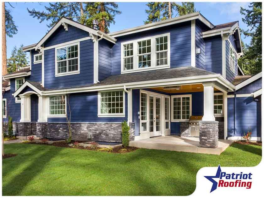 A large blue house with a patriot roofing logo in the corner