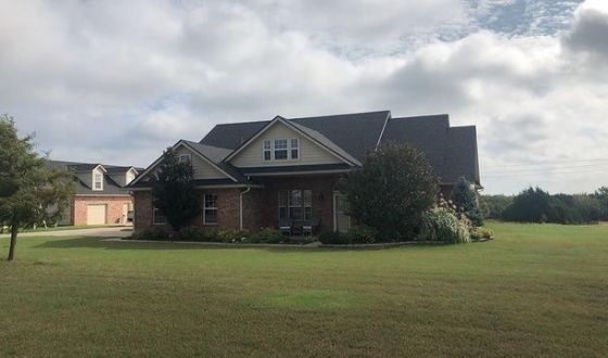 A large brick house with a large lawn in front of it