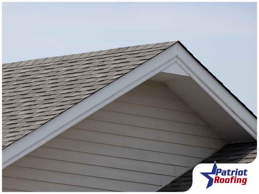 A patriot roofing logo is on the side of a house
