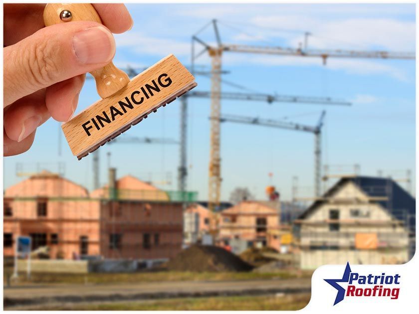 A person is holding a stamp that says financing in front of a construction site.