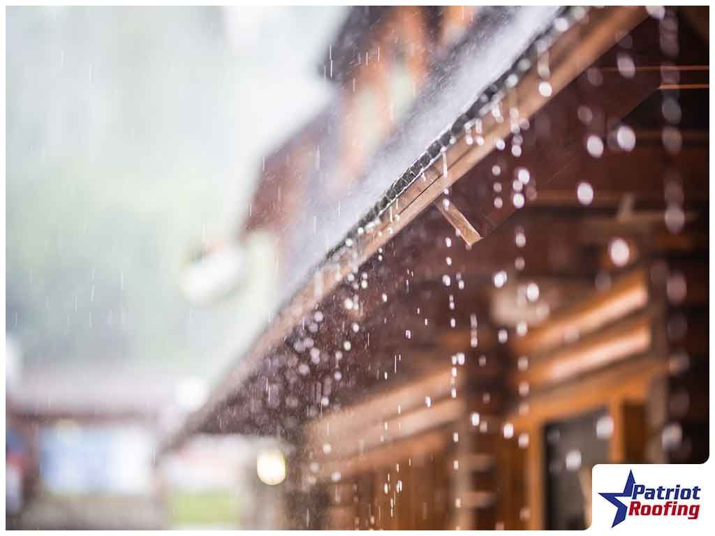 Rain is falling from the roof of a log cabin.