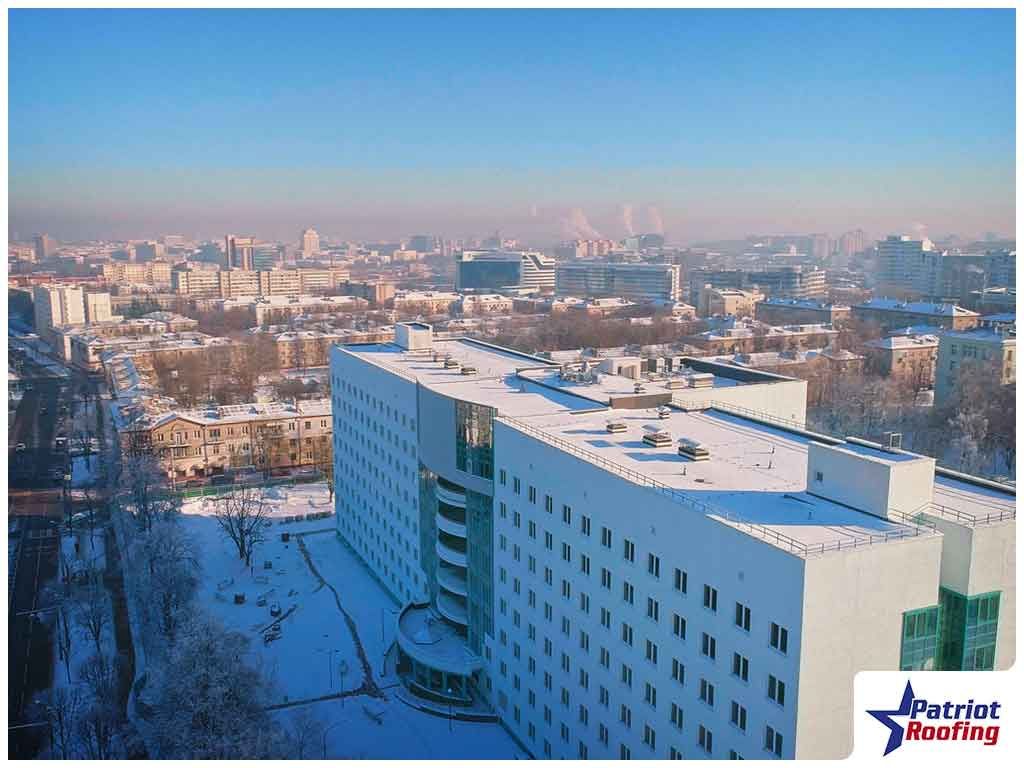 An aerial view of a large white building with snow on the roof
