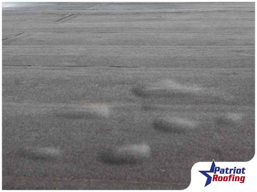 A picture of a roof with a patriot roofing logo in the corner