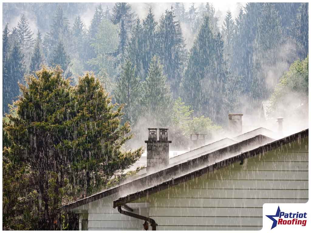 A house with a chimney in the rain with trees in the background.