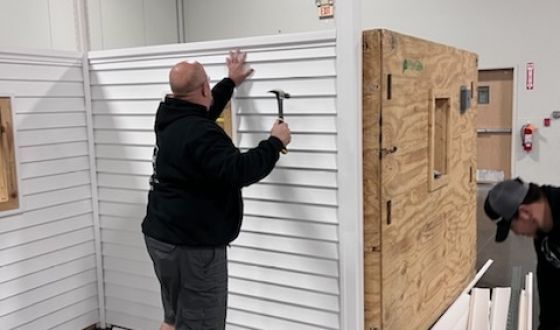 Two men are working on a wall with a hammer.