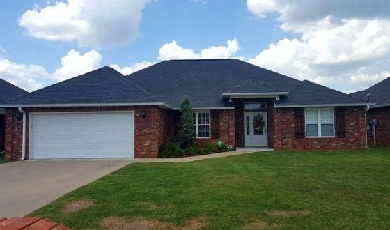 A brick house with a black roof and a white garage door