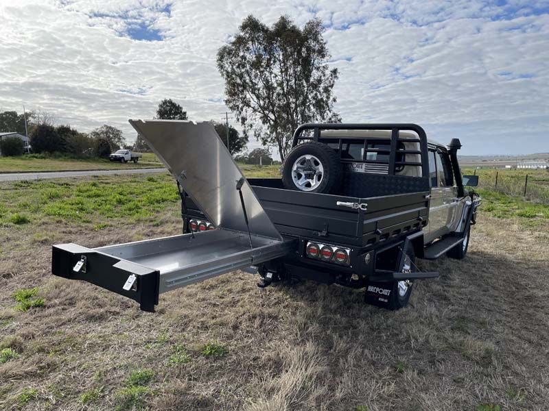 A truck with a trailer attached to the back of it is parked in a field.