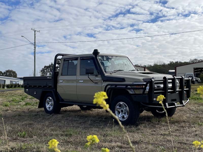 A truck is parked in a field with yellow flowers.