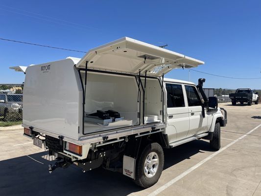 A white truck with a canopy is parked in a parking lot.