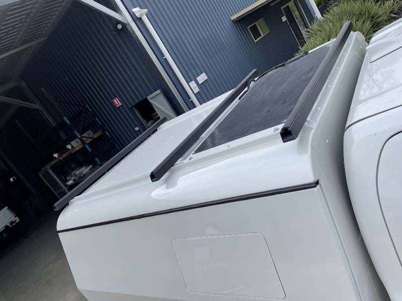 A white truck bed cover is sitting on top of a white truck.