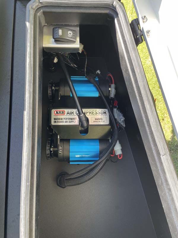 A blue air compressor is sitting in the trunk of a car.