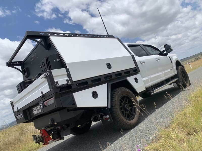 A white truck with a canopy is parked on the side of the road.
