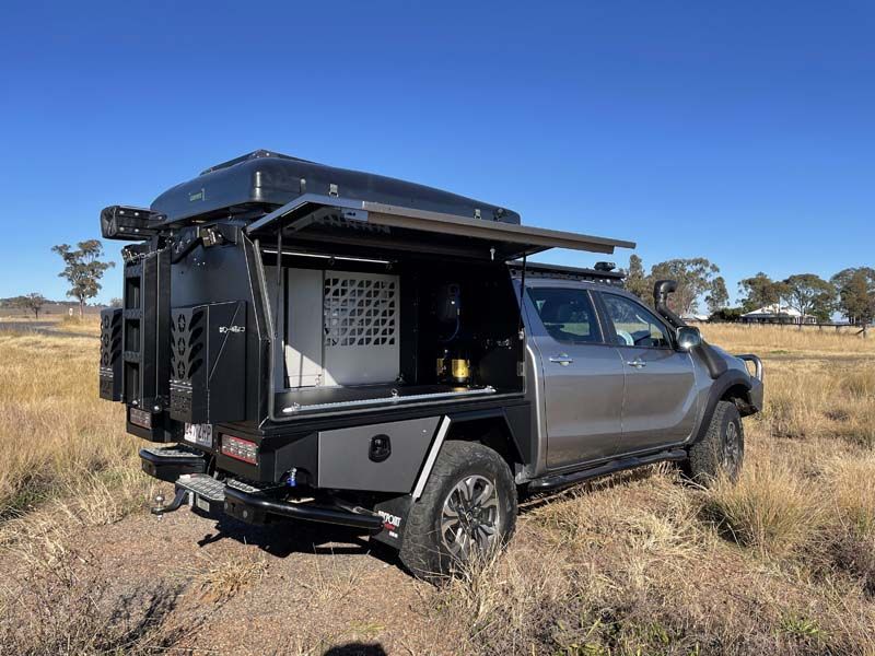 A truck with a canopy on top of it is parked in a field.