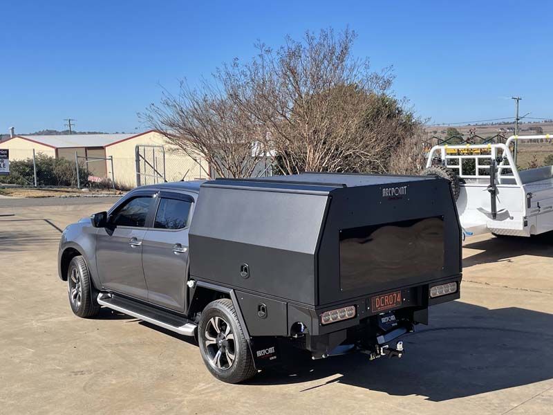 A truck with a canopy on top of it is parked in a parking lot.